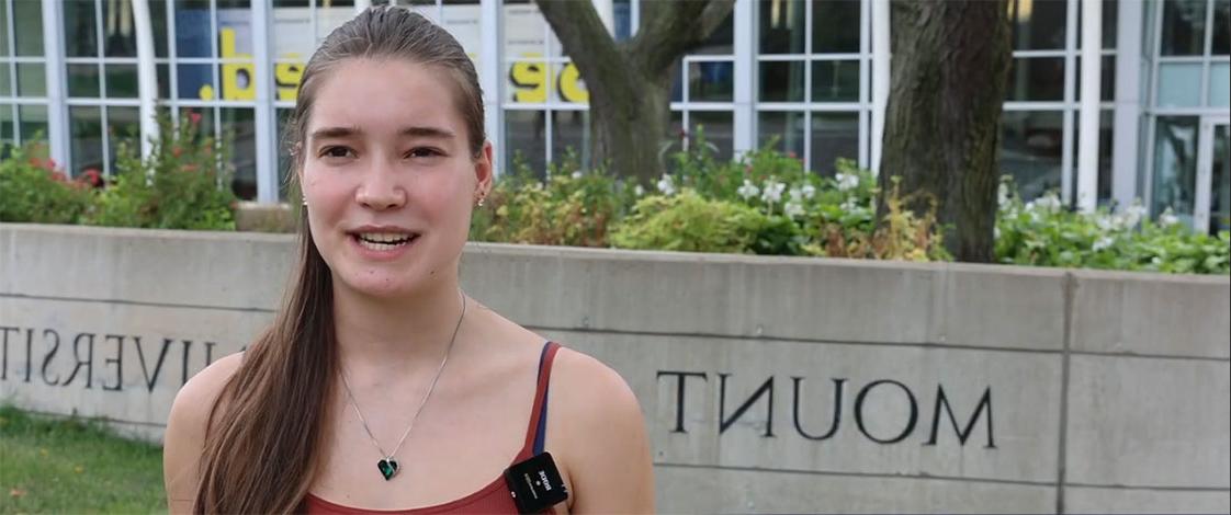 A student on the track, speaking to the camera